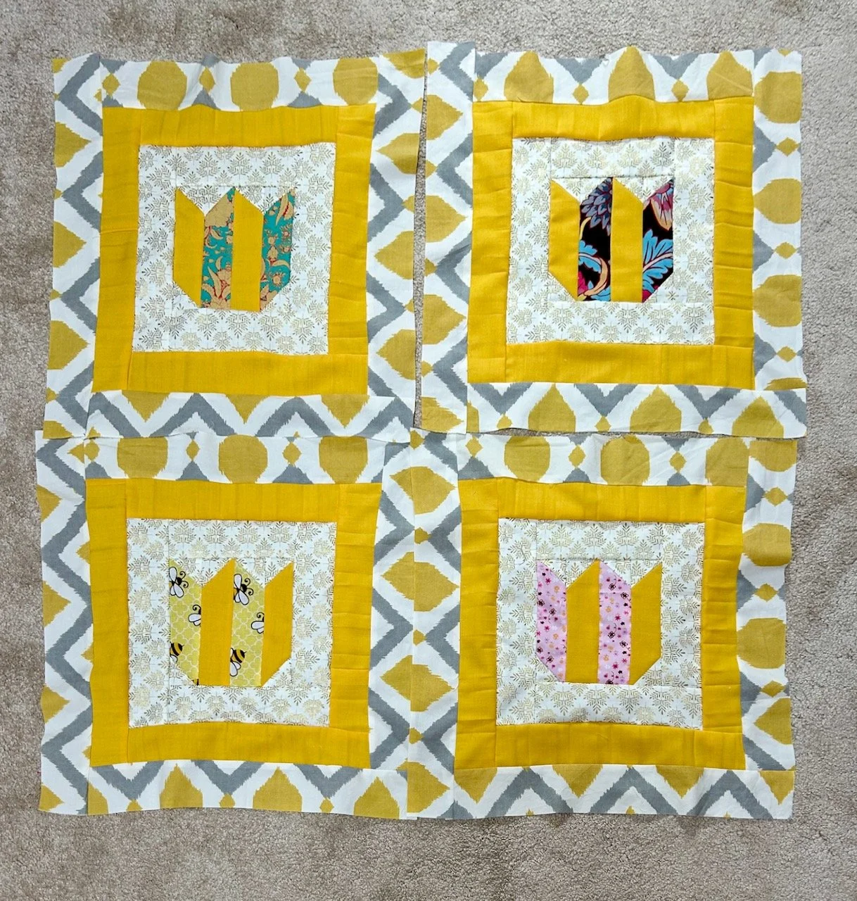 Four blocks edged in white/gold, then pleated yellow and a grey, white and yellow aztec print - laid out in formation