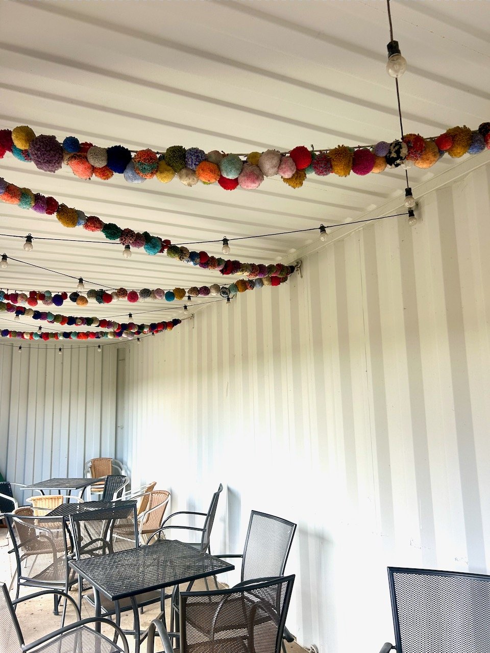 wooly pom poms strung across the ceiling in the cafe's outdoor covered seating area