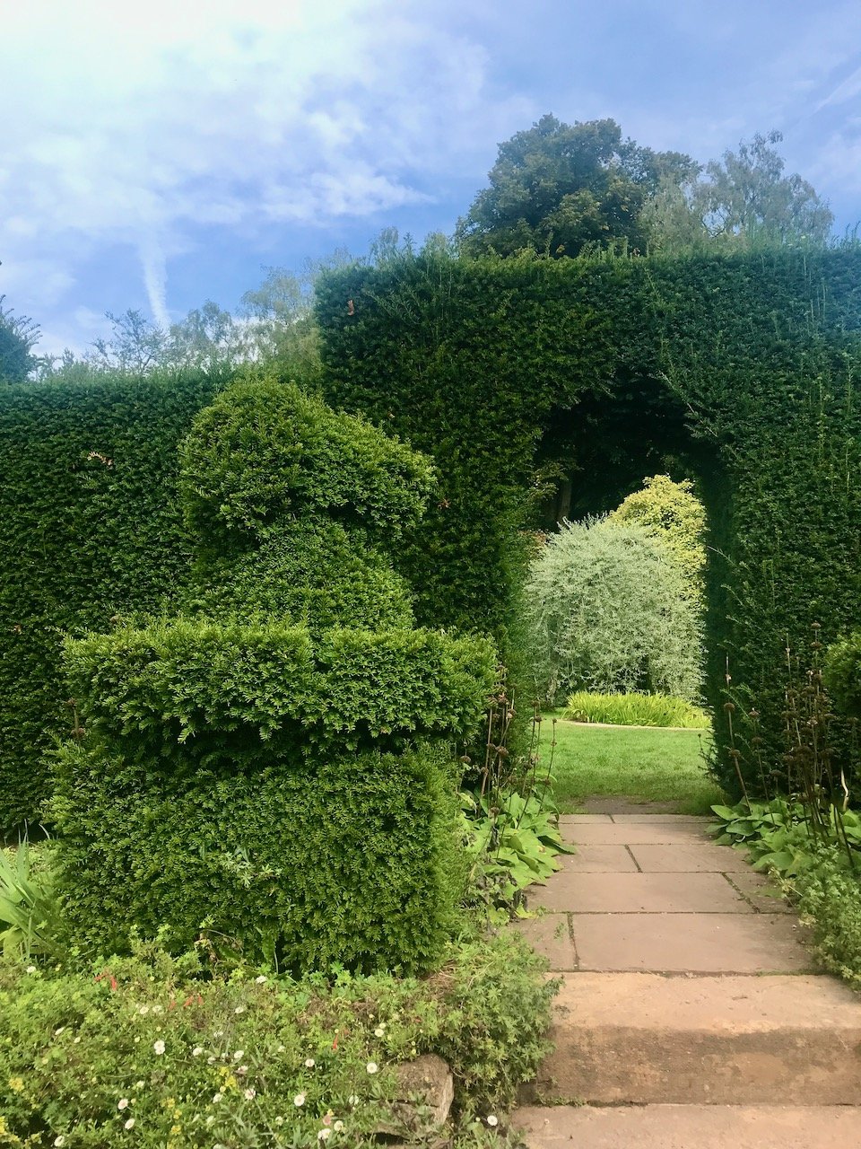 A Yew topiary arch with a dog topiary on the left hand side