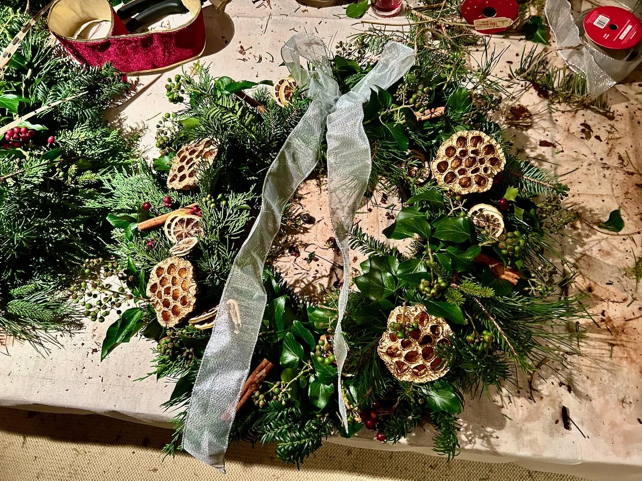 My completed wreath complete with decorations - including a large silver bow, golden lotus flowers, cinnamon sticks and dried citrus fruit