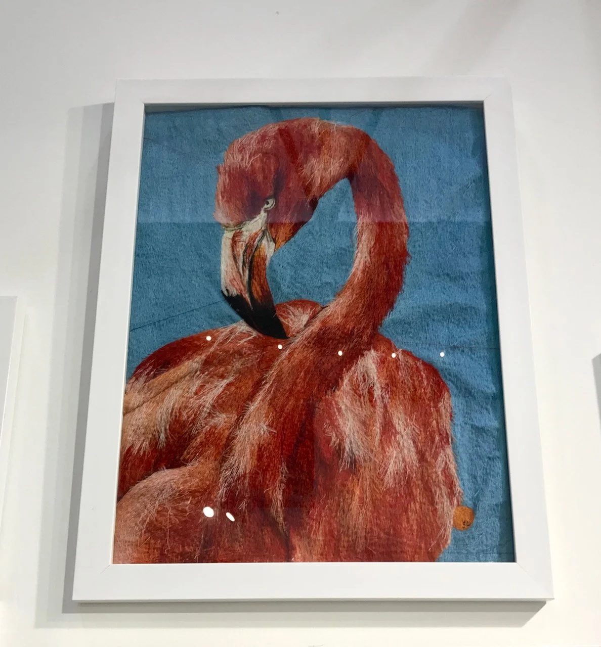 A detailed embroidered flamingo against a blue background