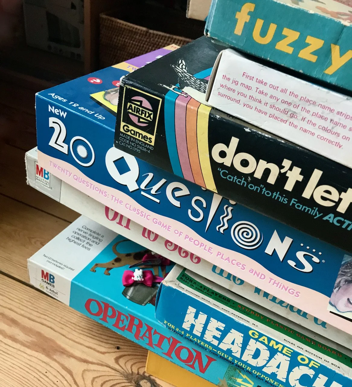 A stack of board games and puzzles on a wooden floor
