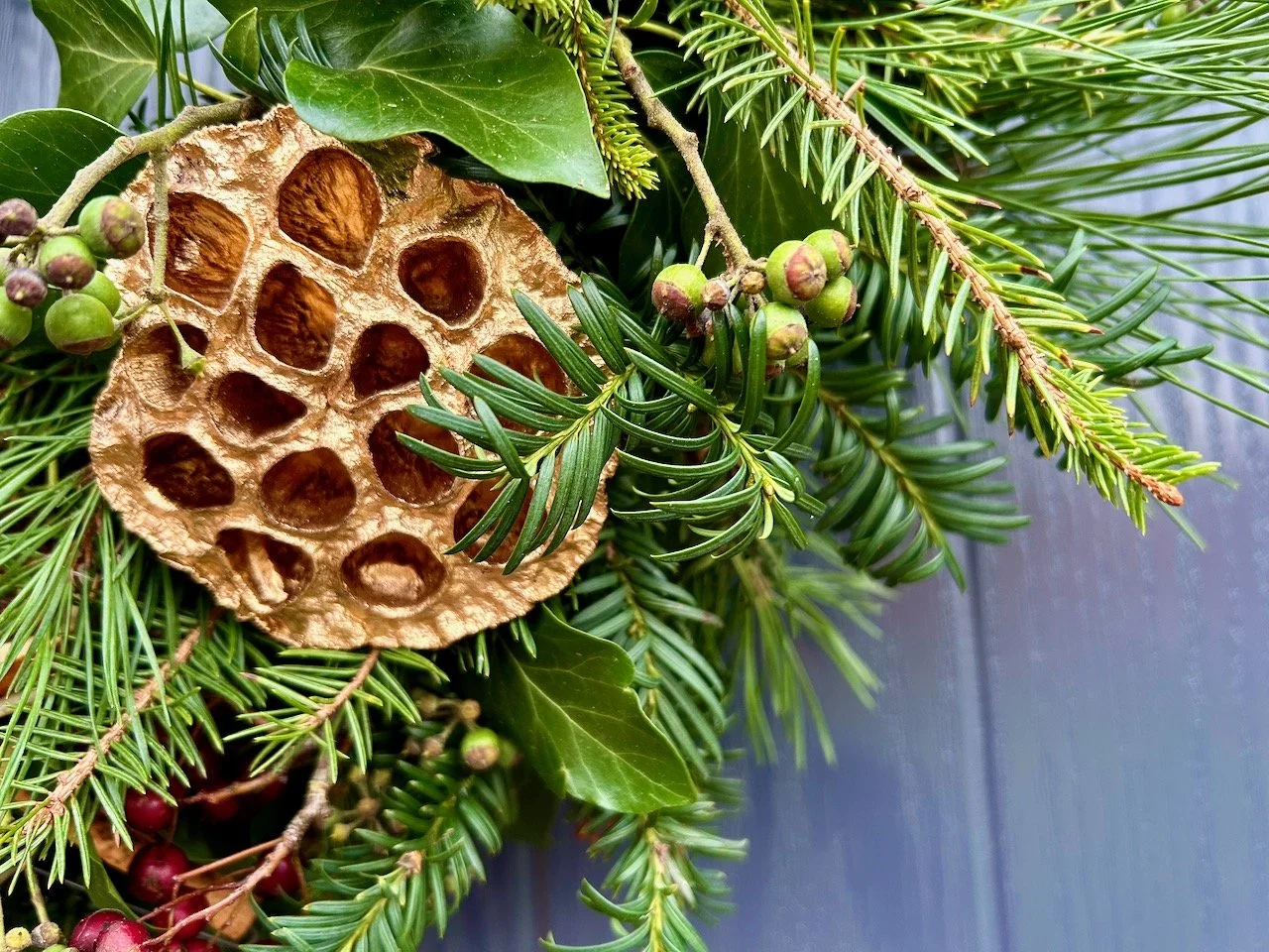 A closer look at the golden lotus flowers, along with yew and ivy greenery, some ivy flowers and red hawthorn berries