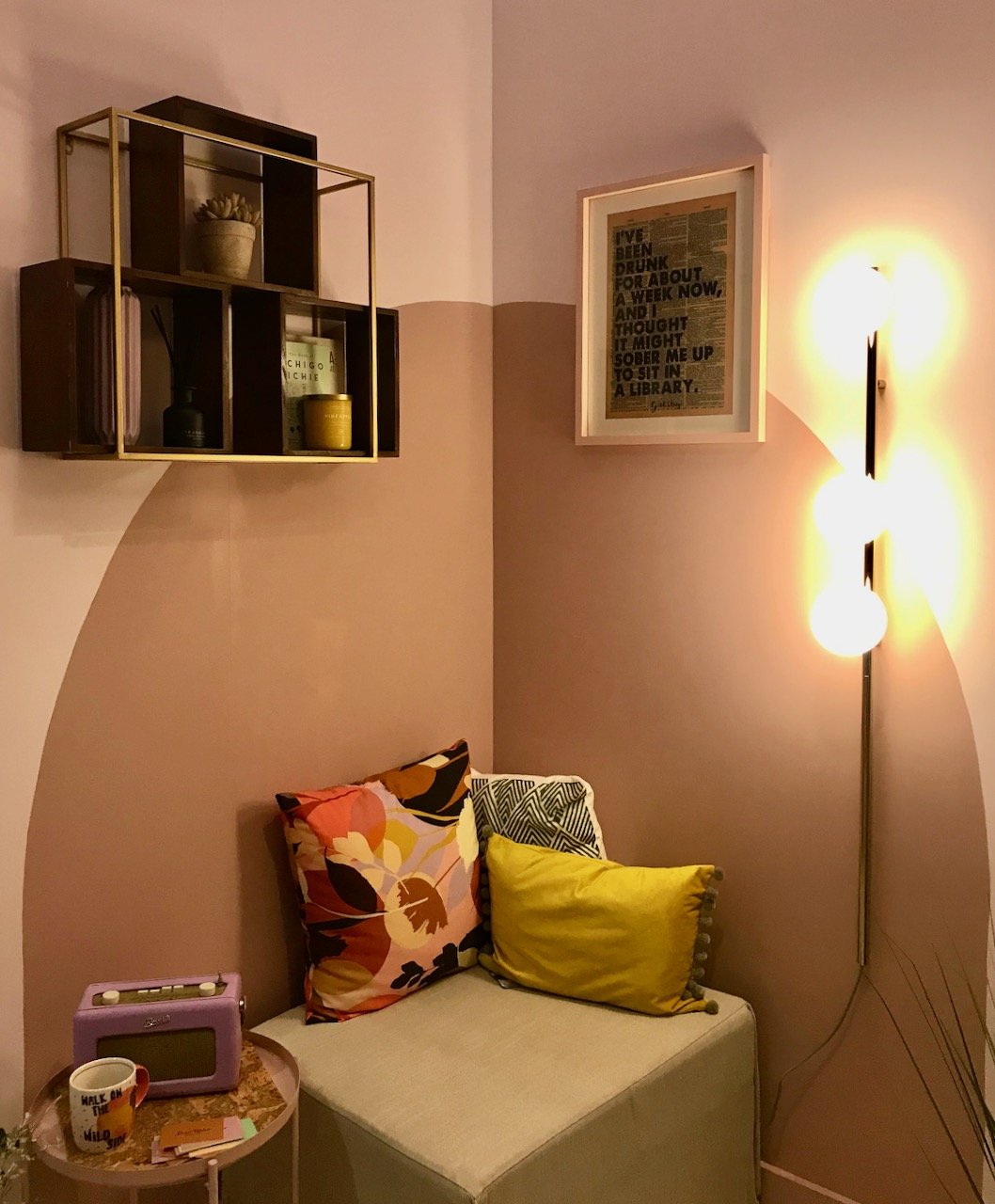 A painted circle on the opposite corner wall with a shelving unit above and an area to relax with cushions, a radio and a cuppa