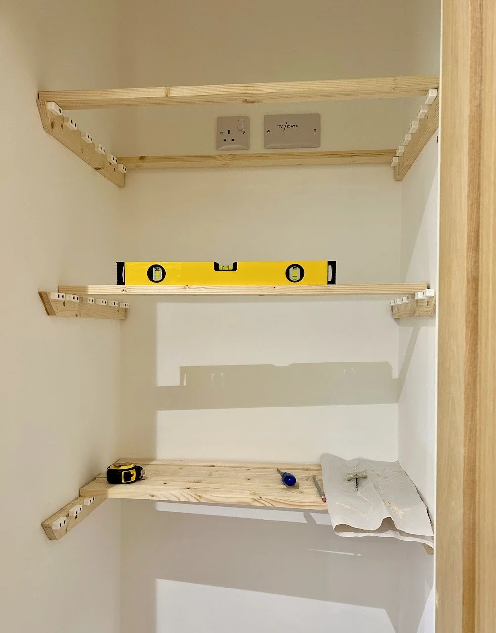The startings of 3 shelves inside my bathroom cupboard with the spirit level across the middle shelf