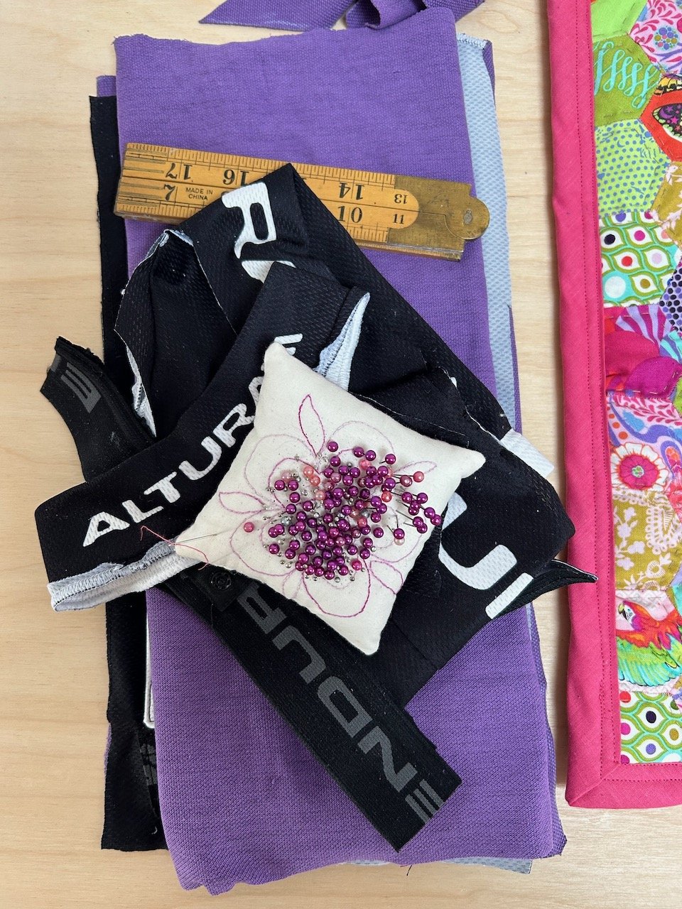 A pile of fabrics from a cycling top, and old t-shirt and elastic from the top of some old cycling shorts ready to be repurposed