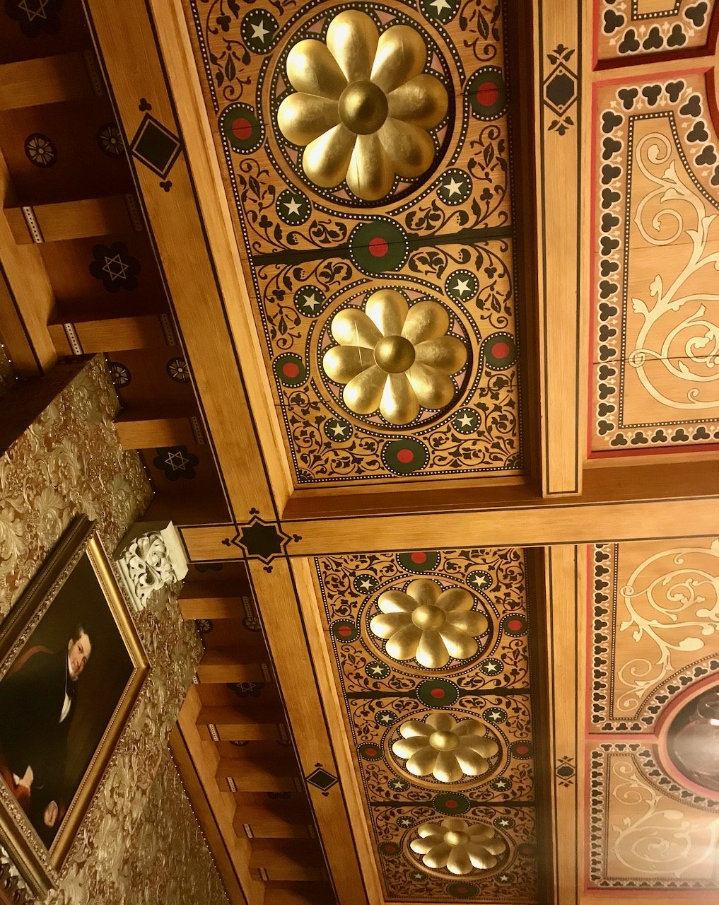 Looking up at fantastically ornate ceilings decorated in panels with gold flowers and green and dotted swirling shapes