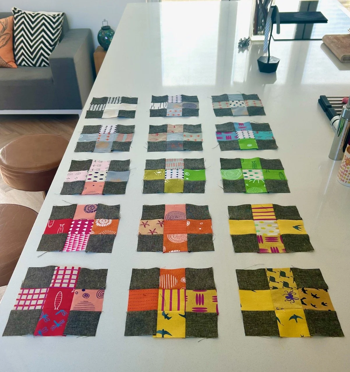 The sewn blocks laid out in a colour progression order with spaces between on my kitchen worktop