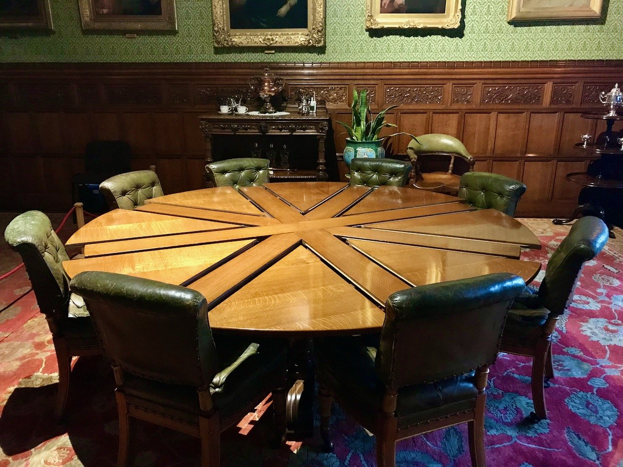 A circular wooden table which extends into a much larger table through sections which form a round  'union flag'