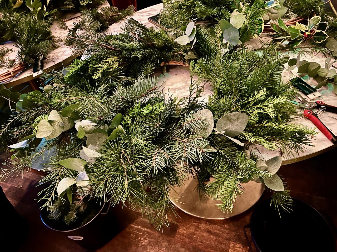 In progress - adding a mixture of green foliage to the wicker ring