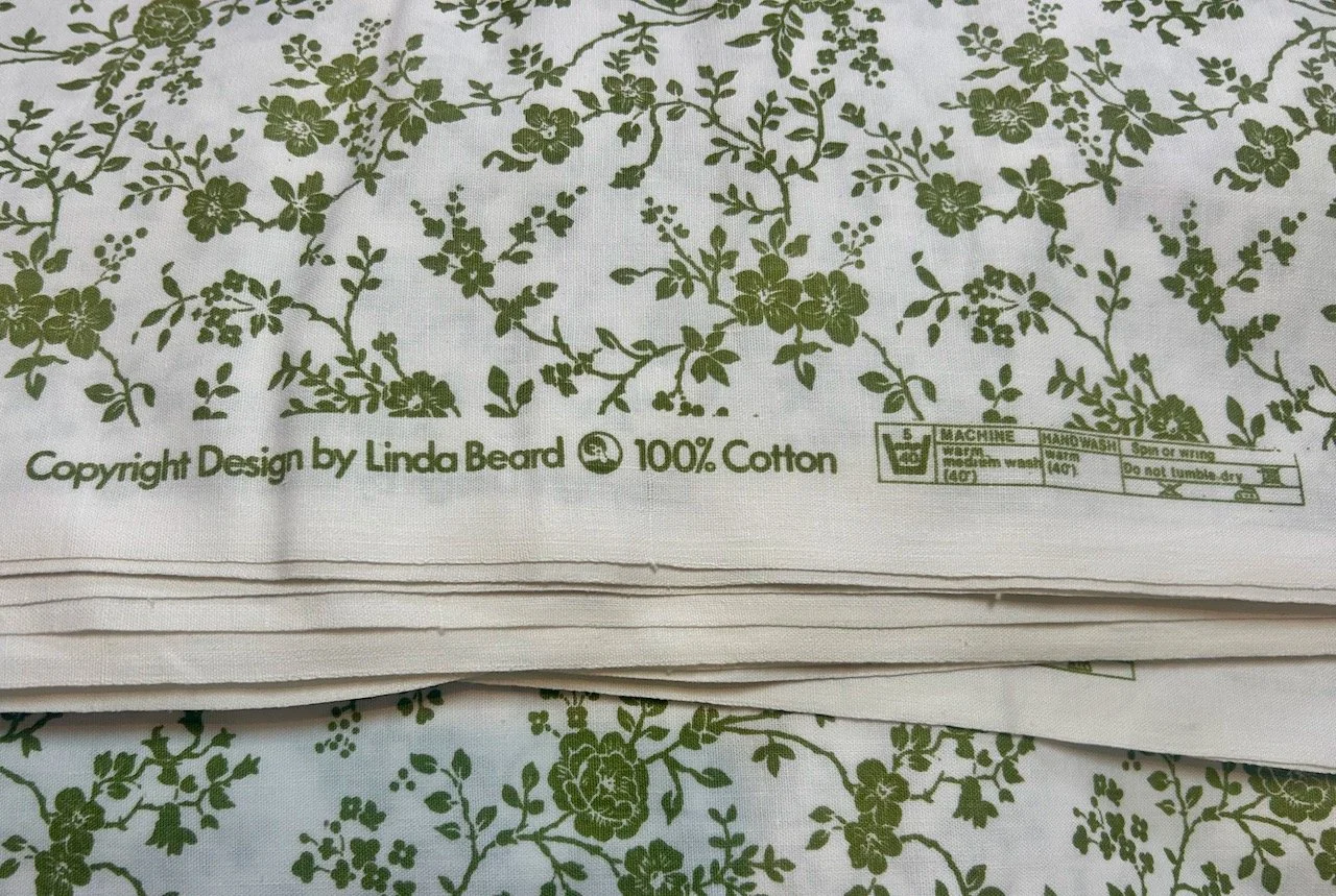 A green floral design on white cotton fabric designed by Linda Beard