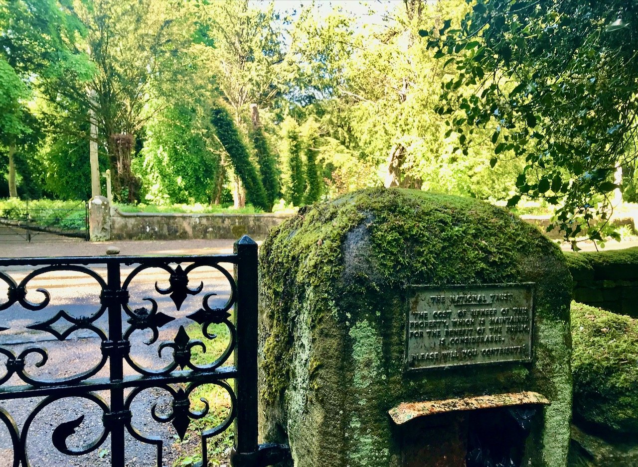 part of an ornate iron gate and a moss covered pillar on the Wallington NT Estate