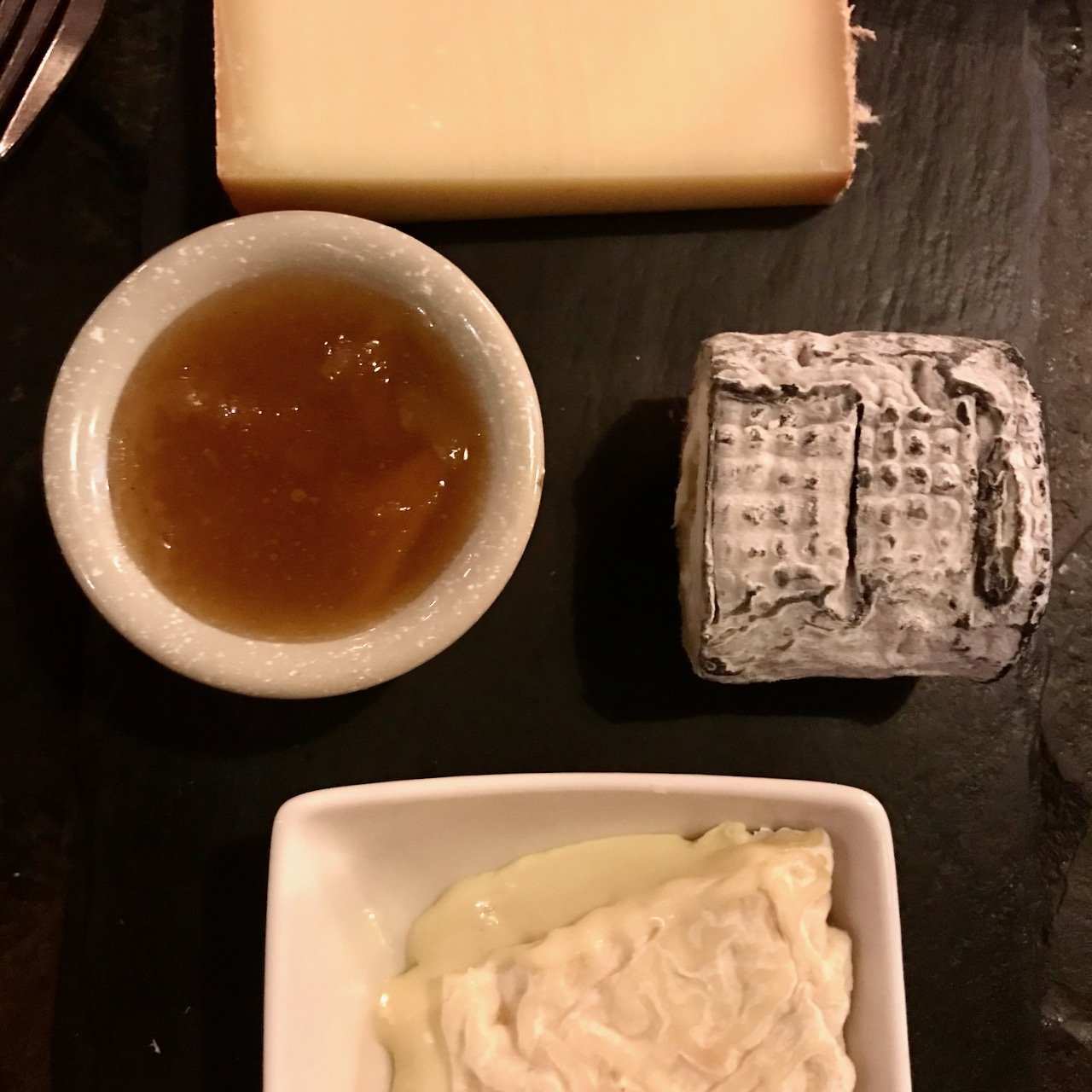 Three cheeses and a chutney on a black slate