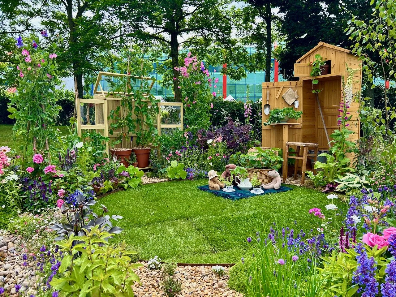 Viewing the garden from the side shows the small greenhouse with tomato plants in pots