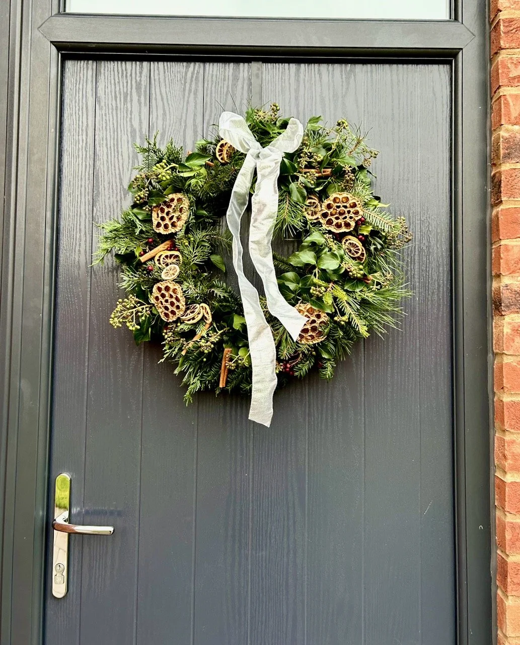 A full length shot of the completed wreath on our dark grey door - which really sets off the silver bow