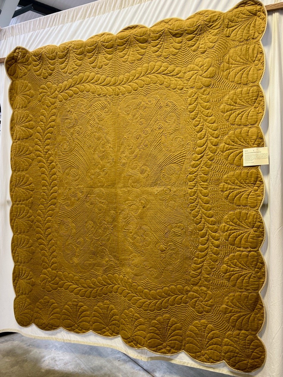 A 'one piece' quilt in mustard with ornate detailing in the quilting