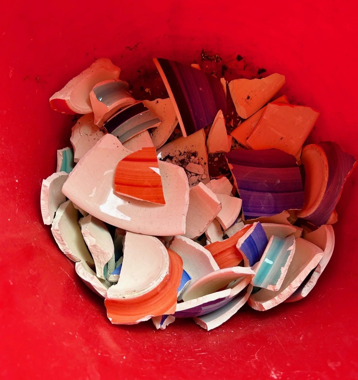 Broken crockery in a red trug