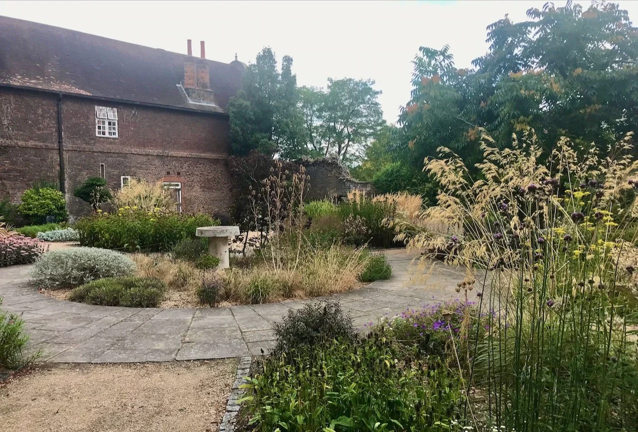 The centre of the garden with central bed, path around and a brick building in the background