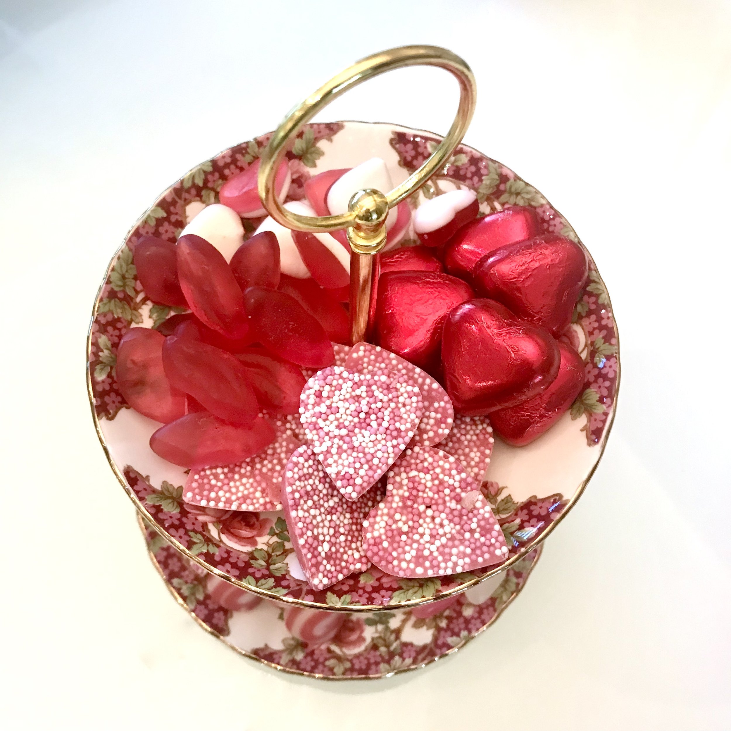 Looking down onto the cake stand with pink hearts, juicy red lips, milk chocolate hearts and more