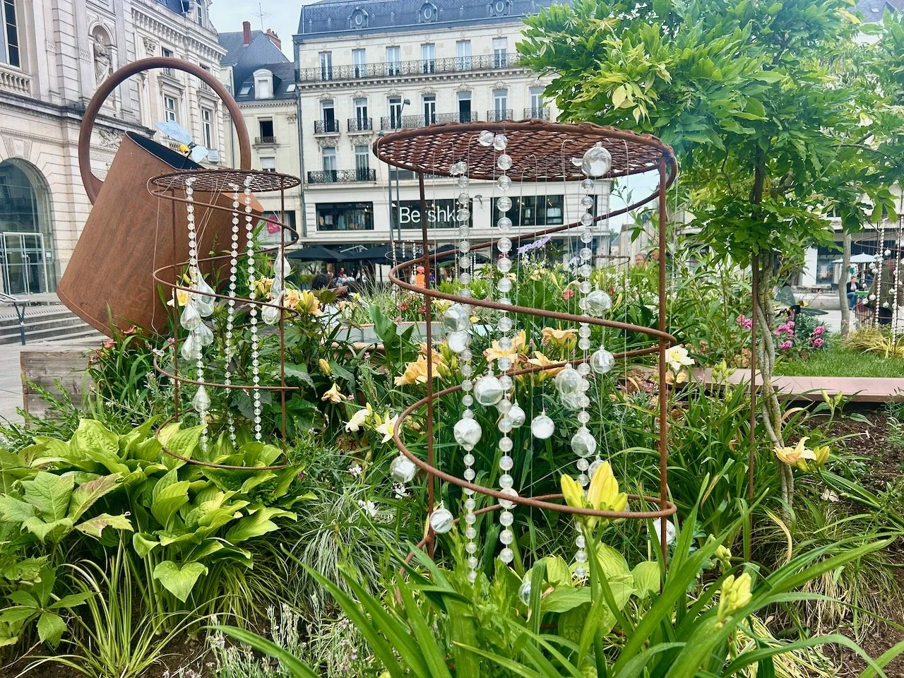 A display in the centre of Angers showing a giant iron watering can and beads as water trickling down spiral plant supports