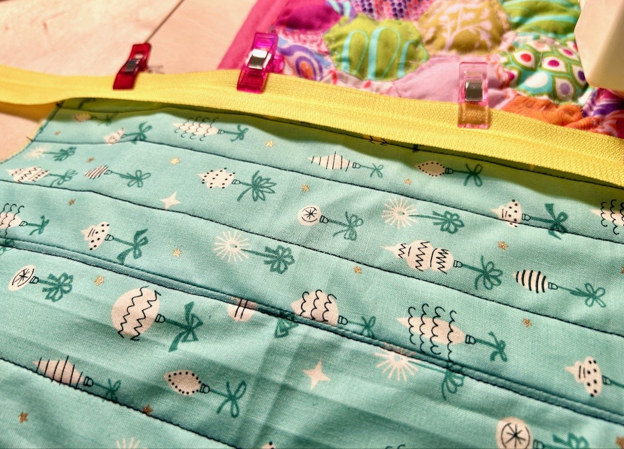 Adding the zip to the hastily quilted aqua fabric with christmas baubles on