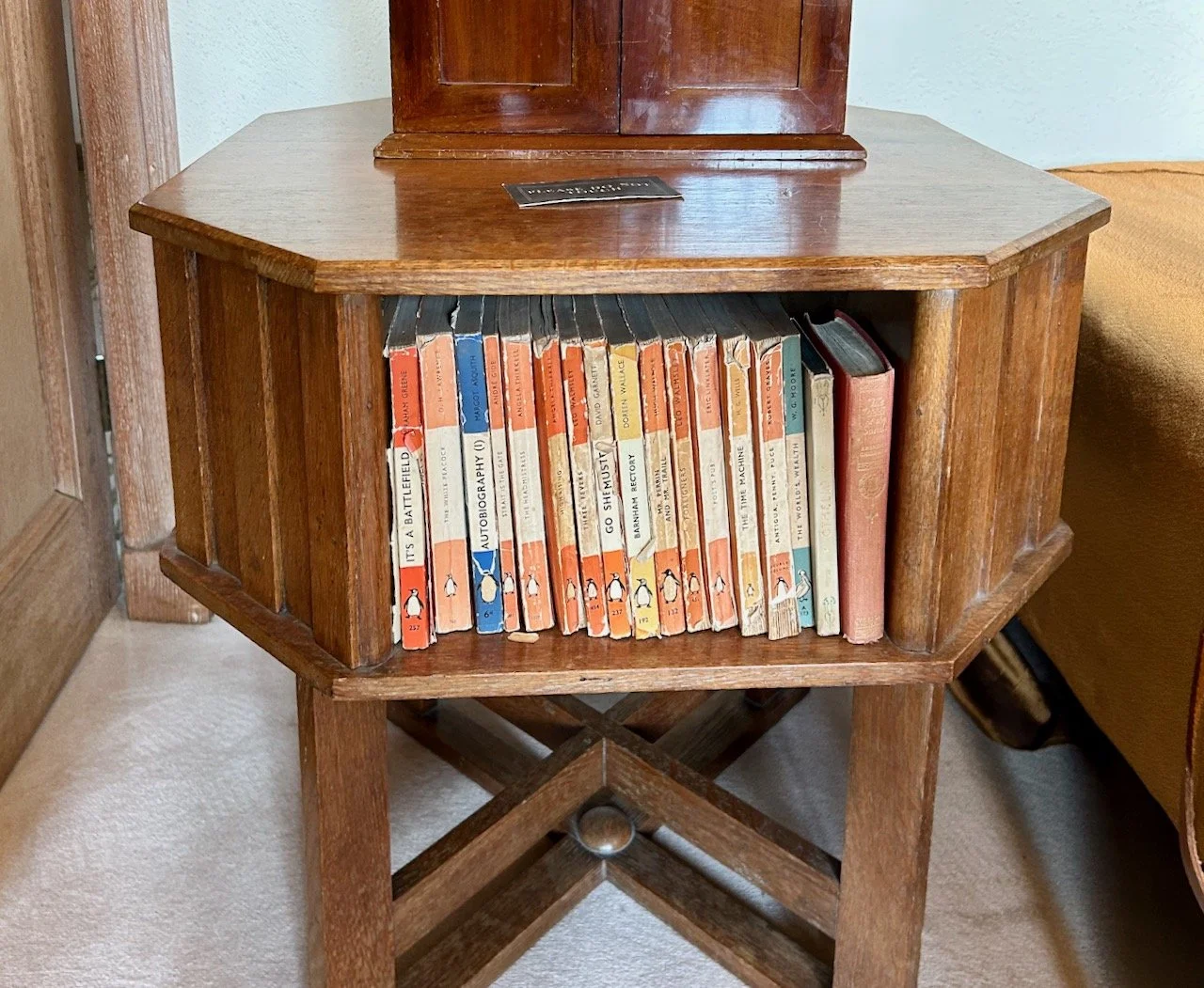 A wooden hexagonal side table with space to hold a well read collection of penguin books