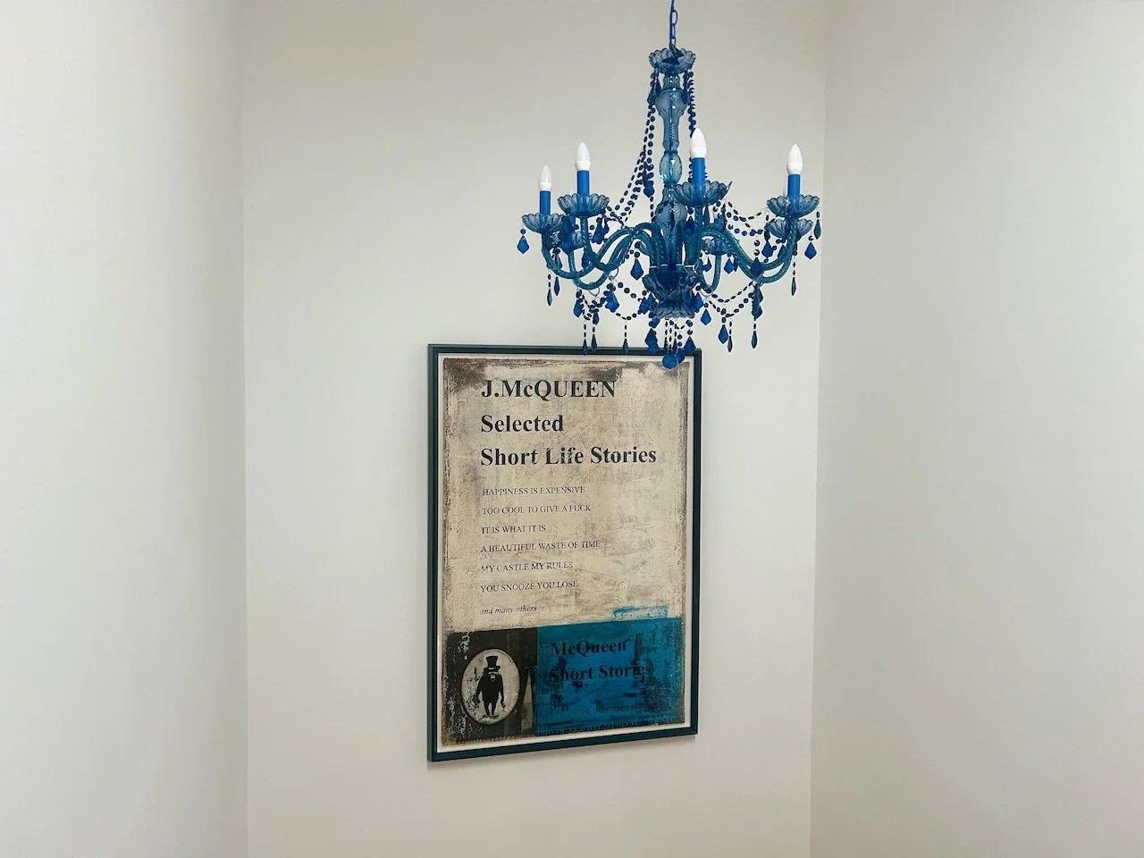 The blue chandelier hanging in the stairwell with our McQueen picture behind it
