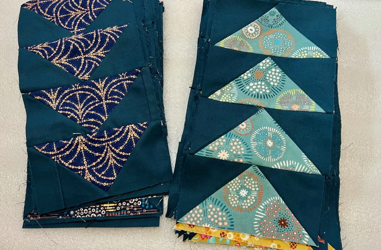 Two piles of completed flying geese blocks