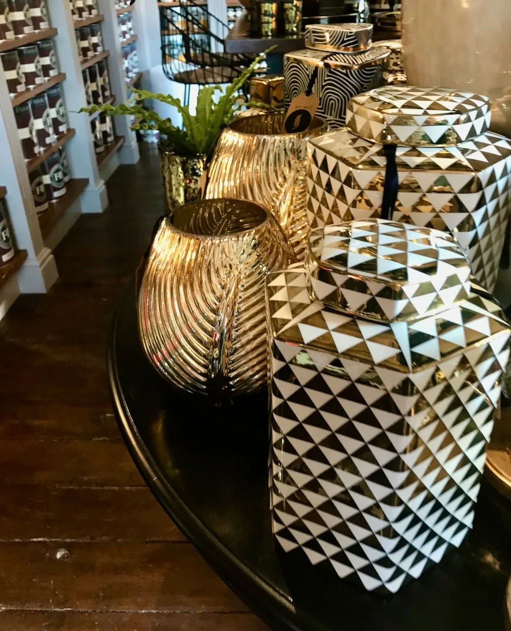 Black and white geometric patterned lidded pots alongside golden leaf imprinted vases