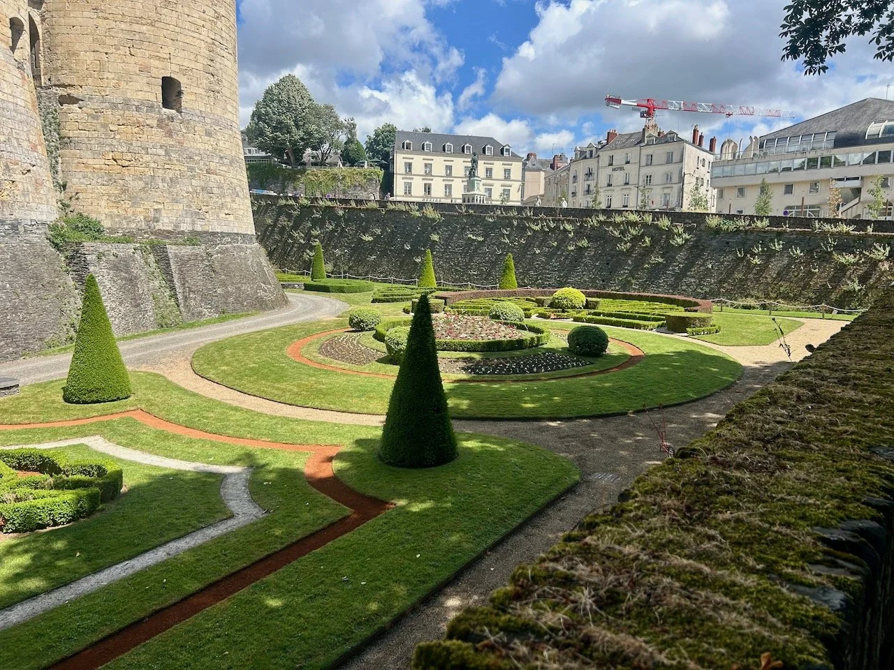 A circular lawn with topiary shapes in the moat of the castle