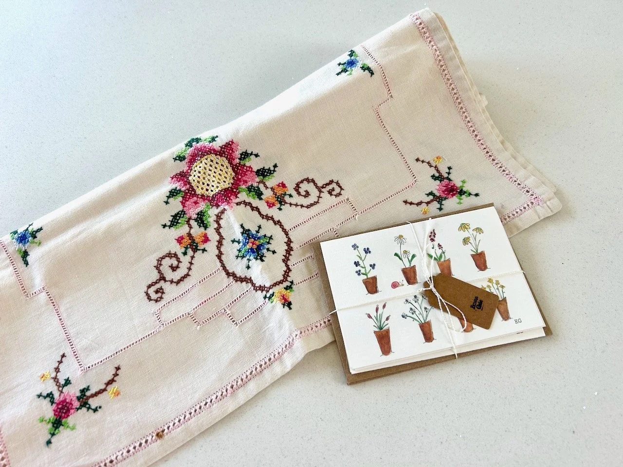 A vintage cross stitch table runner, with small handpainted notelets resting against it