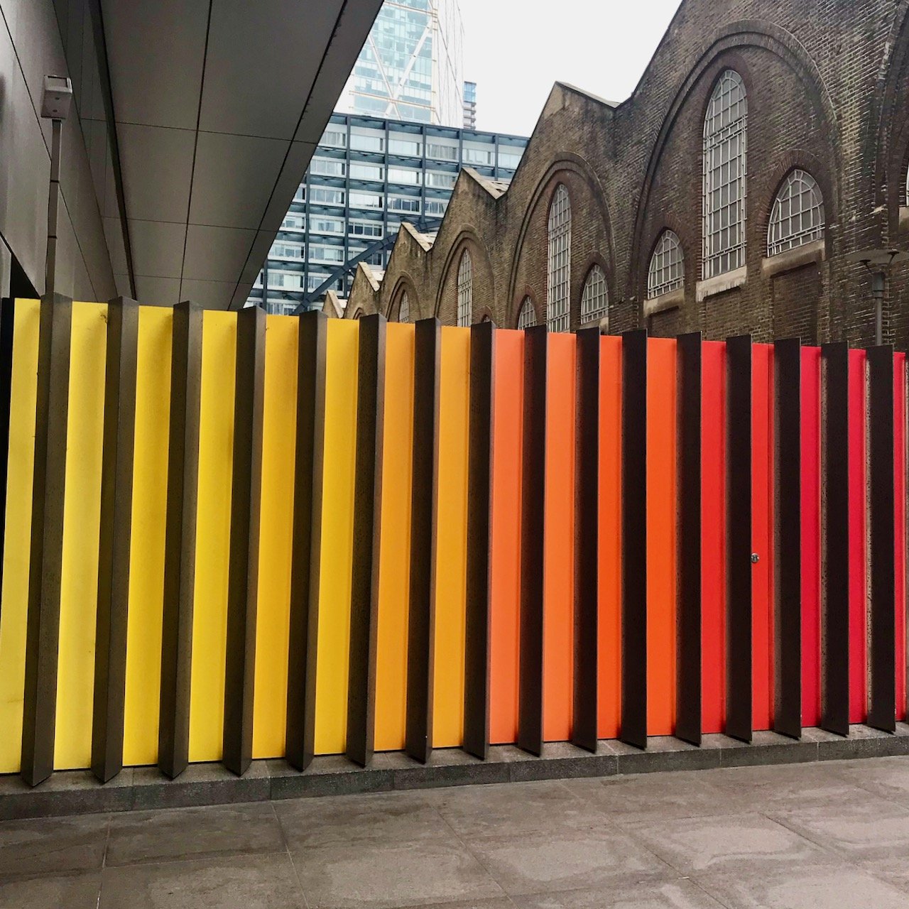 A modern sculpture at Liverpool Street - panels of yellow through orange and red with black uprights in between