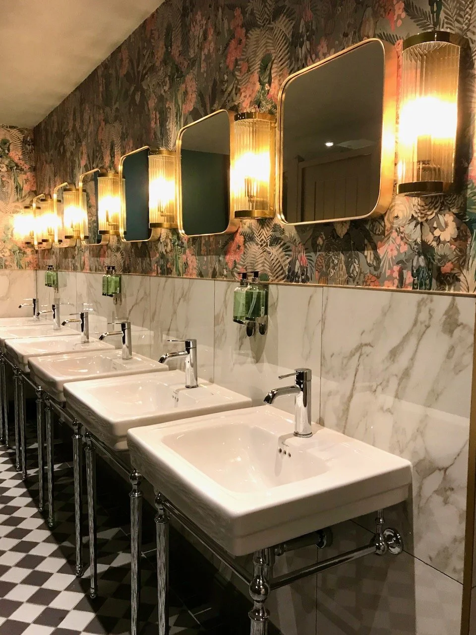 the wallpaper, mirrors, lights, tiles, sinks on legs and flooring