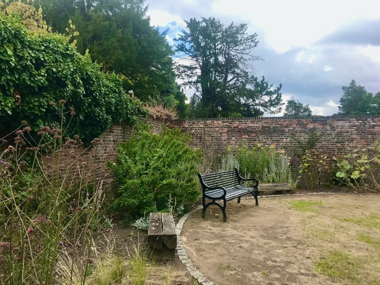 A metal bench flanked by two wooden benches on the edge of one of the lawns