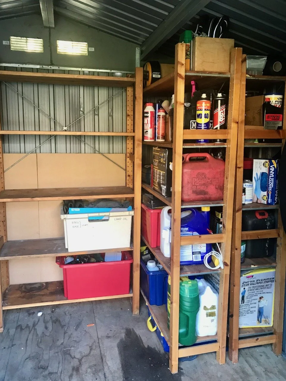 looking inside the shed at the three shelving units, which are neater and still have space