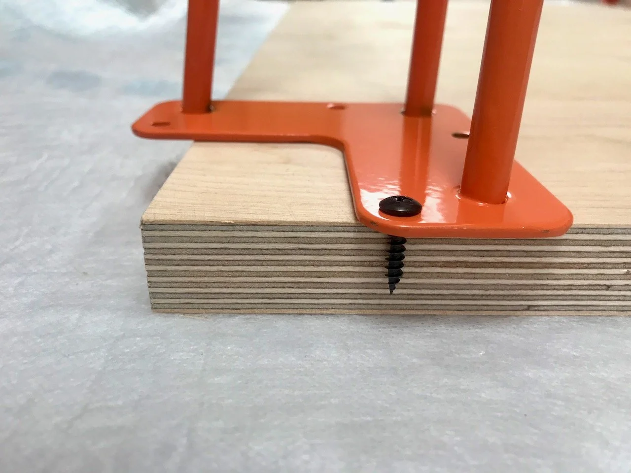 Assembling the desk - the corner of the plywood top with the leg and screw being positioned and checked for depth
