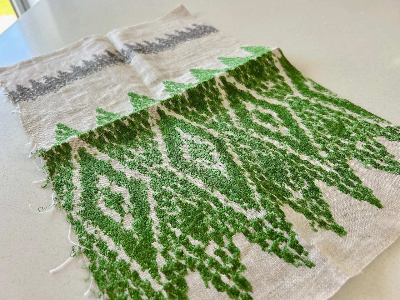 A £1 fabric sample with a bold embroidered green diamond pattern