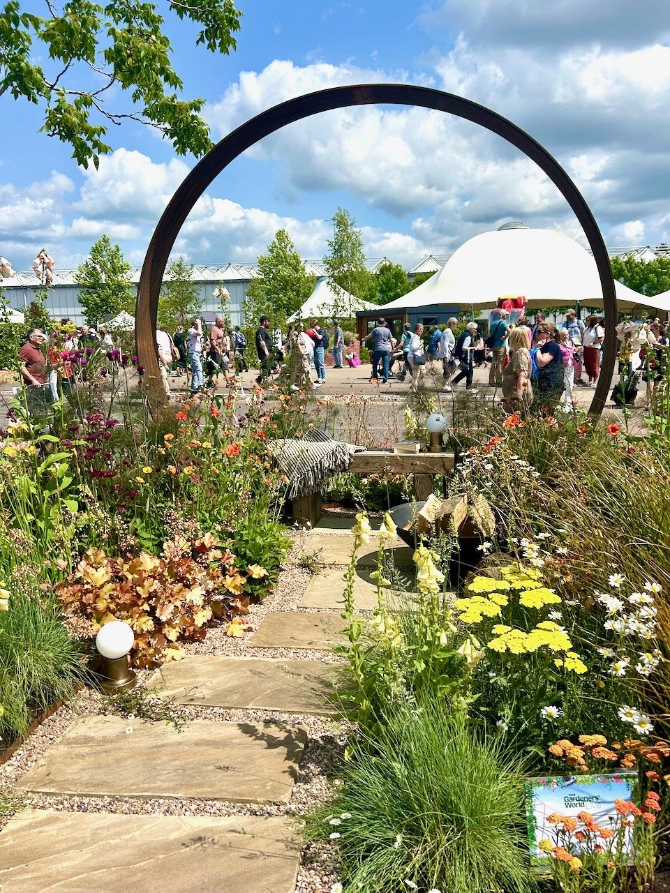 Looking at the full border (with the tents and people at the show behind) and enjoying the rusty metal arch with the relaxed planting in the foreground