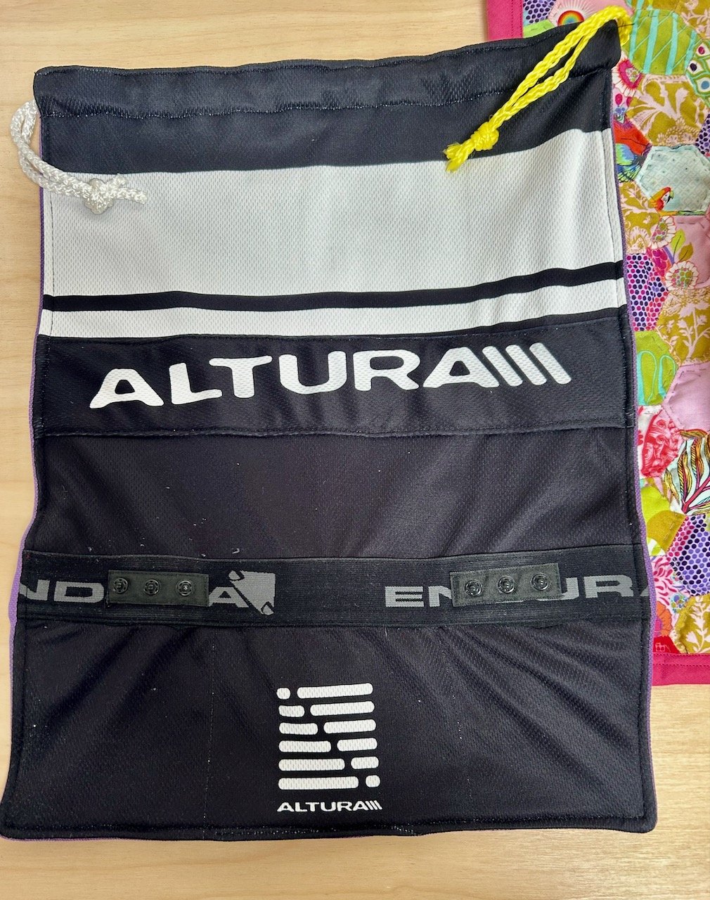 THE BACK OF THE BAG USES THE BACK OF THE CYCLING TOP WITH ADDITIONAL LOGOS ADDED AND ELASTIC TRIM SEALING THE POCKETS