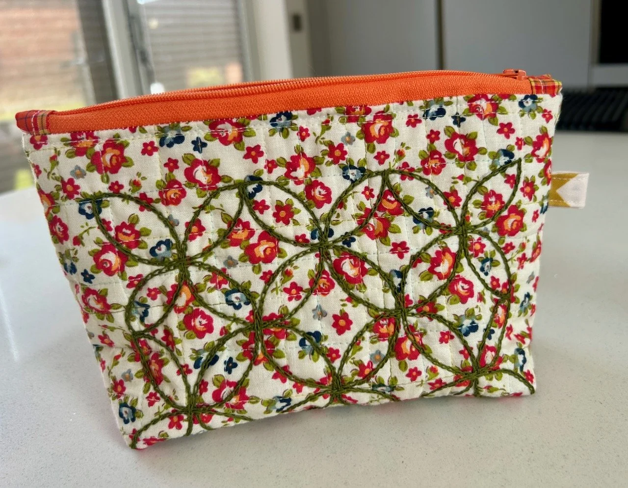 The reverse: embroidered green interlocking circles on a small flowered background