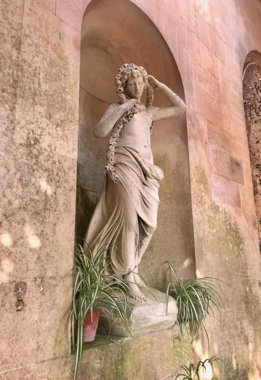 a female statute in an alcove with spider plants at feet level