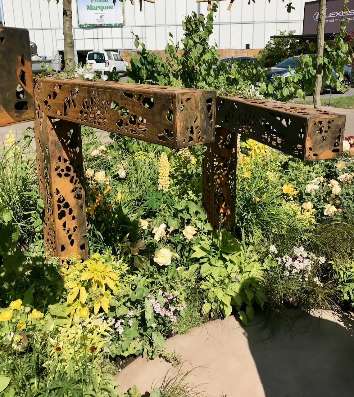 Two further reverse L shaped corten posts, these are much smaller and the planting around them is yellow and green