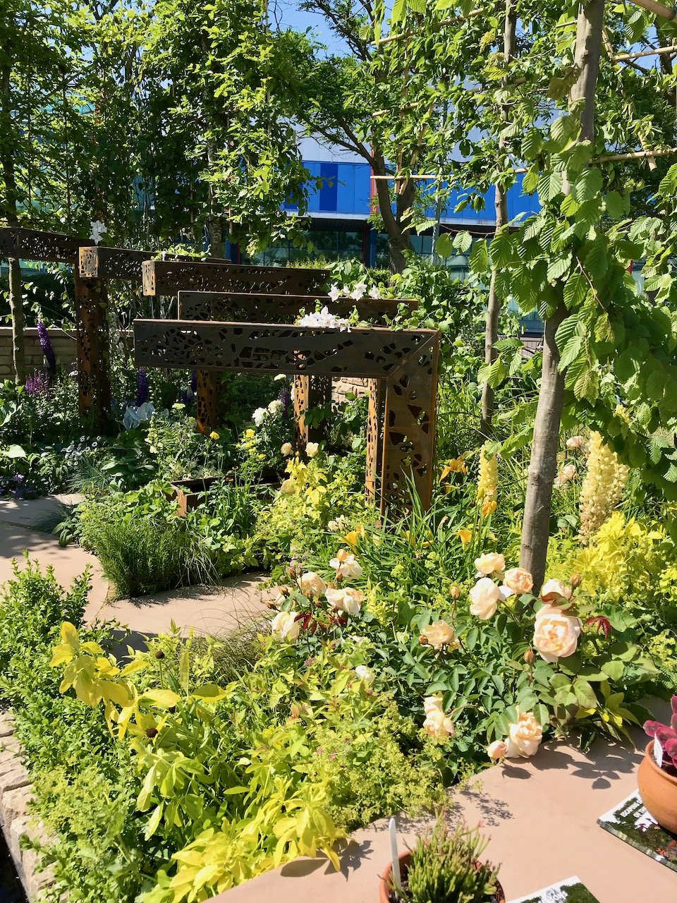 A series of increasing height corten steel posts form a circle around the garden representing time