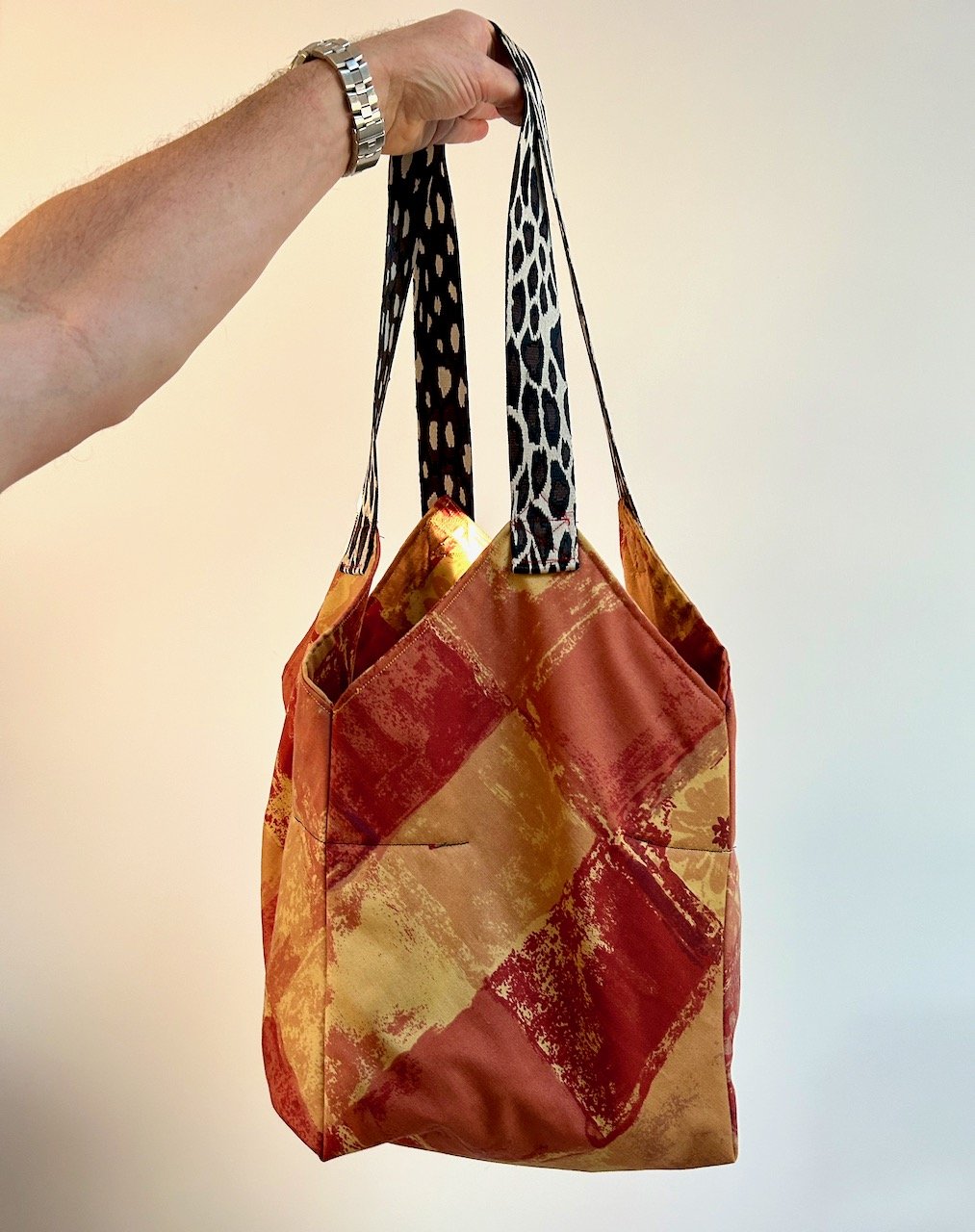 The finished bucket bag made from orange and mustard material (old curtains), the leopard print webbing handles held up by MOH