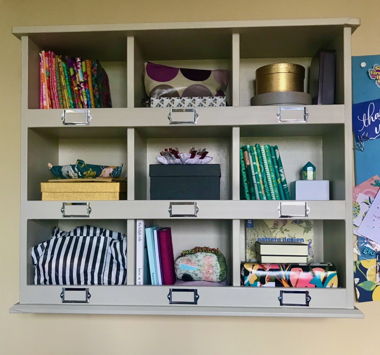The pigeon shelves hung back on the wall, with craft supplies in each of the 9 holes (but not too many this time!)