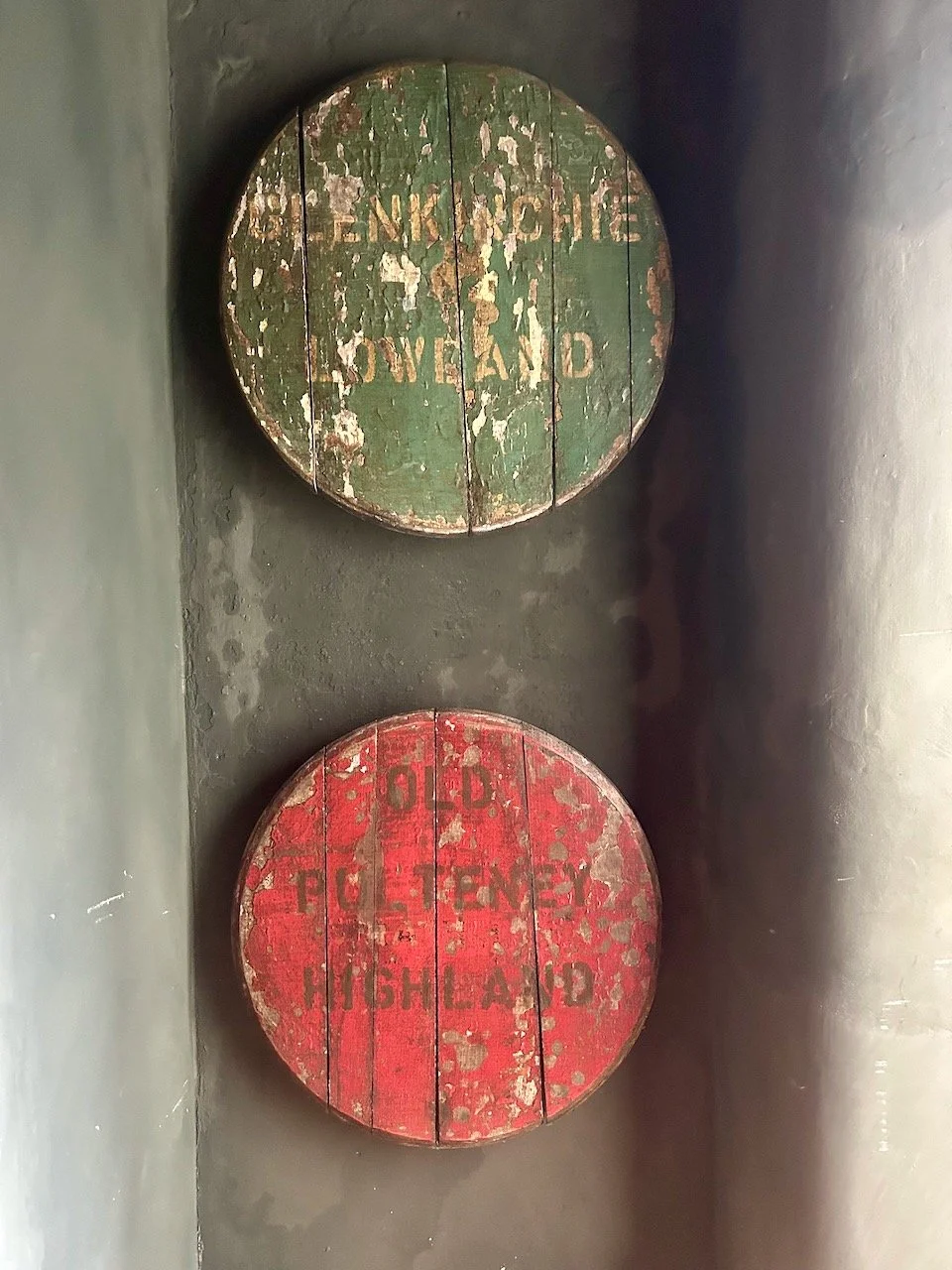 Two weathered wooden what look like barrel tops - one green, one red