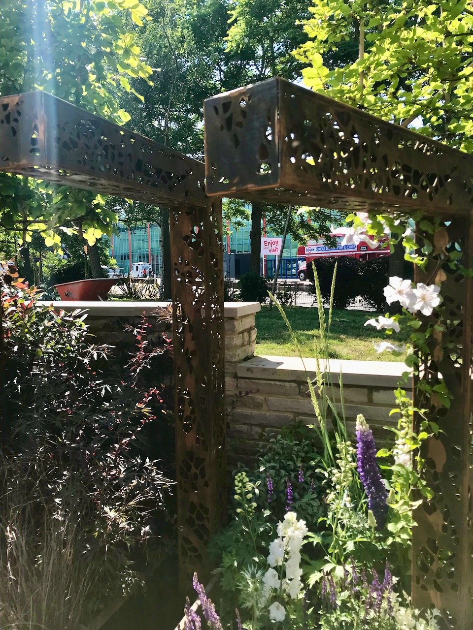 A closer look at two of the corten steel upside down L shape posts with purple and white planting beneath