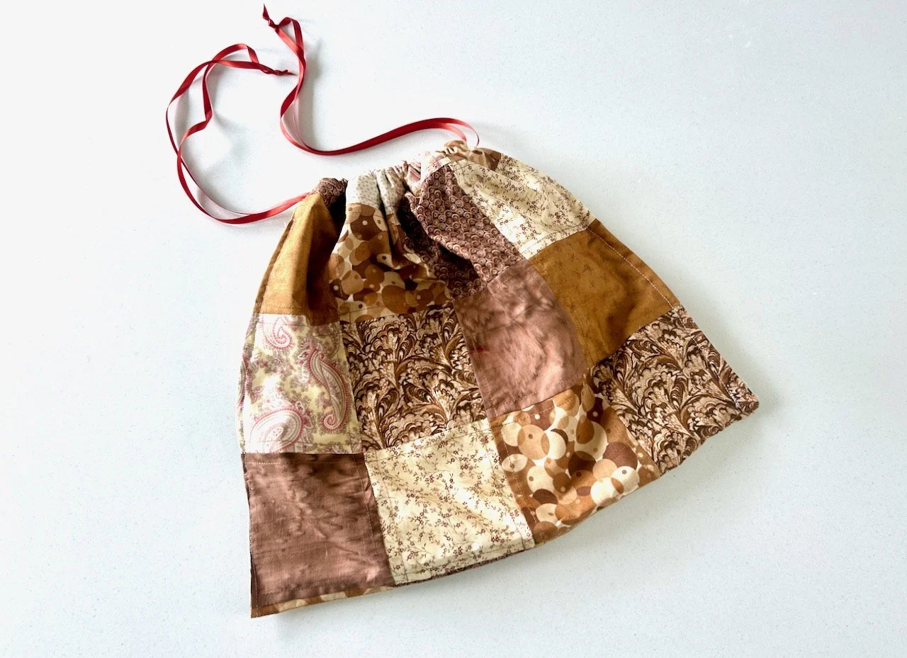 A brown patchwork drawstring bag made from the scraps