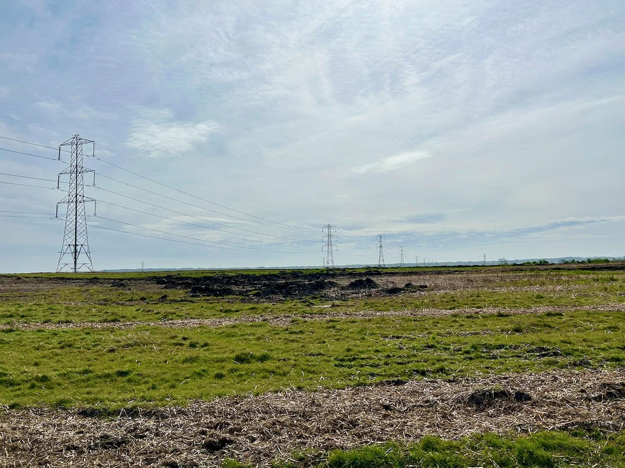 a field with pylons in the foreground stretching into the distance