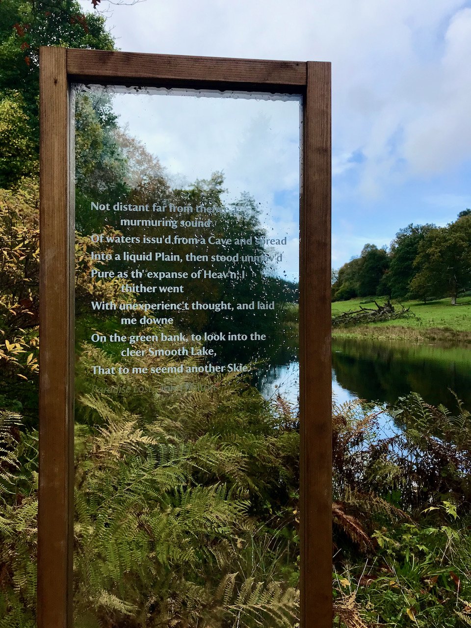 a quote etched on glass in a wooden frame/stand in front of the lake